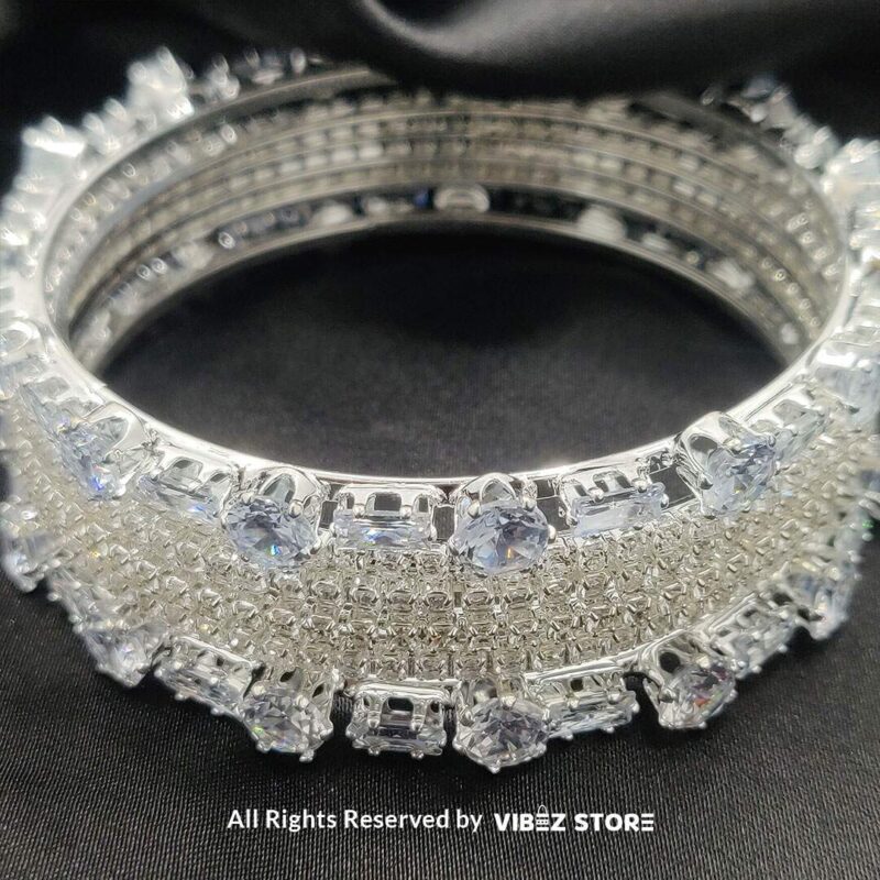 Sparkling Silver-Toned Crystal Bangle Set 4 Silver-toned crystal bangle set with intricate detailing on a black background