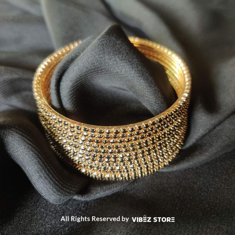 Multi-Layer Black Crystal Gold Bangle Set 2 Multi-layer gold bangle set with black crystal accents on a black fabric background