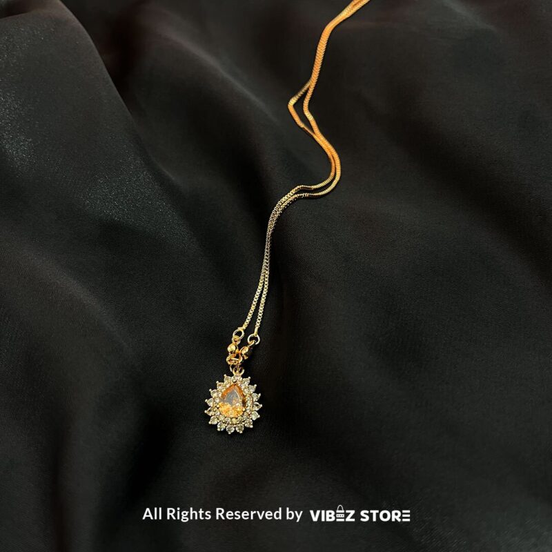 Teardrop Crystal Locket 2 Teardrop Crystal Locket in amber, emerald, and turquoise colors with gold chains on a black background