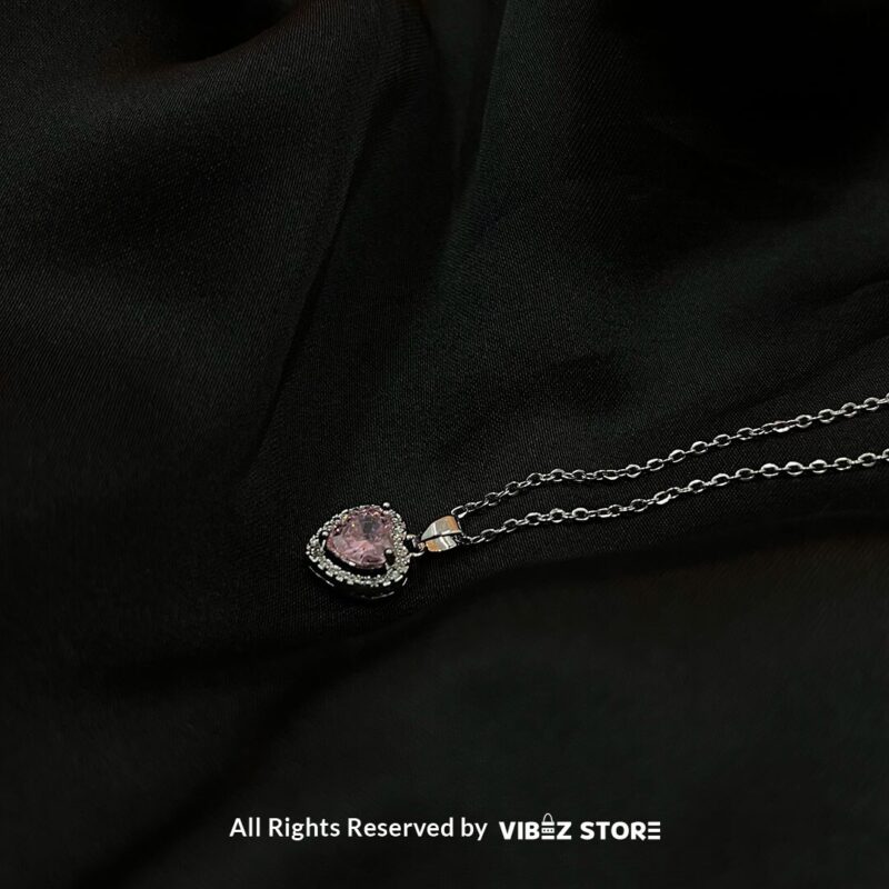 Heart-Shaped Pink Gemstone Locket 1 Heart-Shaped Pink Gemstone Locket with silver-tone chain on a black background
