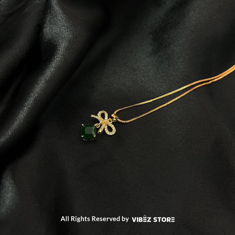 Bow-Embellished Square Gemstone Locket 4 Bow-adorned Square Gemstone Locket in red, green, black, and turquoise colors with gold chains on a black background