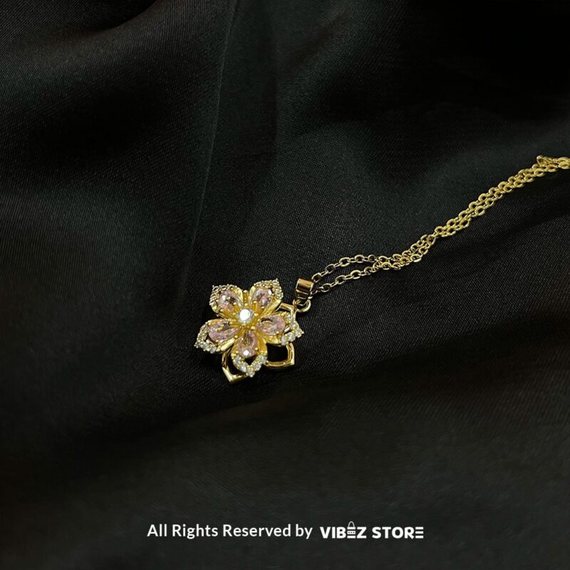 Floral Gemstone Locket 1 Floral Gemstone Locket with pink crystals and gold-tone chain on a black background