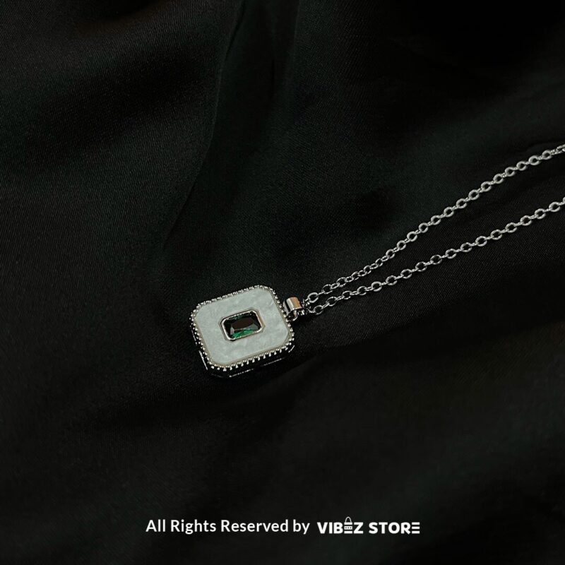 Square Gemstone & Mother-of-Pearl Locket 1 Square Gemstone & Mother-of-Pearl Locket with green gemstone and silver-tone chain on a black background
