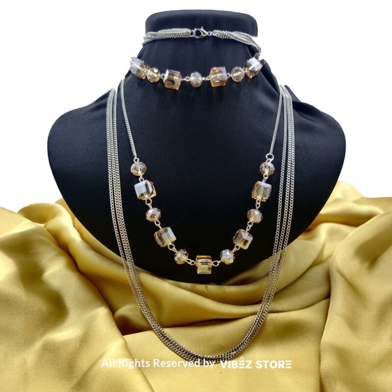 Elegant Crystal Cube and Chain Necklace Set 1 Elegant crystal cube and silver-tone chain necklace set on a black bust with yellow fabric background