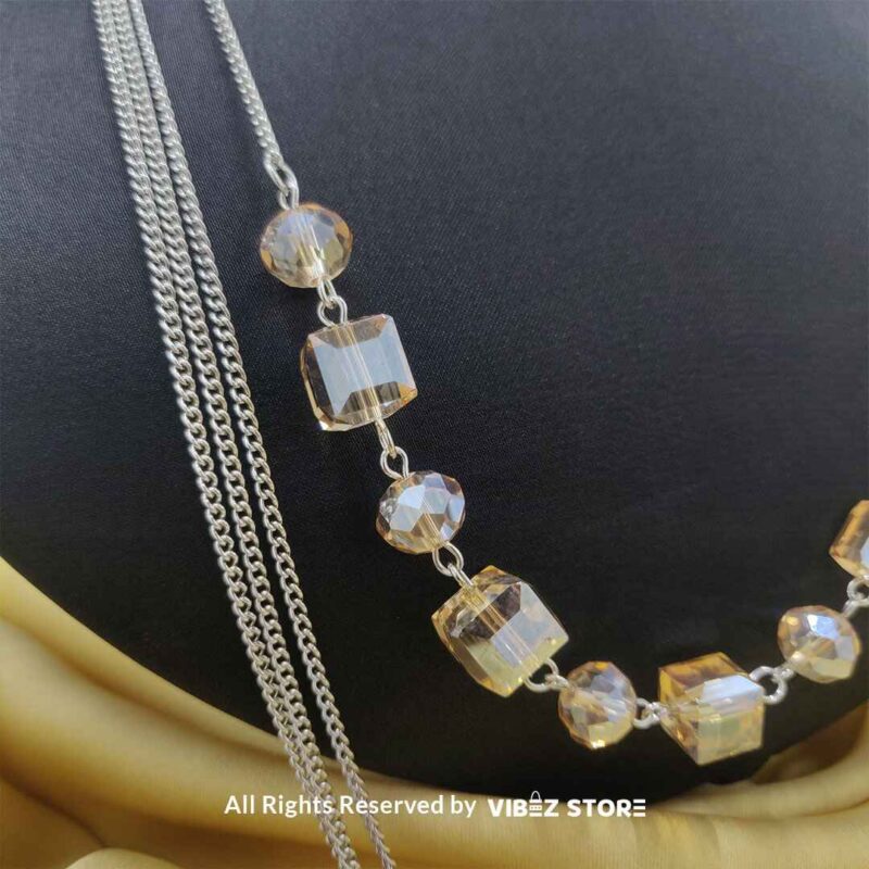 Elegant Crystal Cube and Chain Necklace Set 2 Elegant crystal cube and silver-tone chain necklace set on a black bust with yellow fabric background