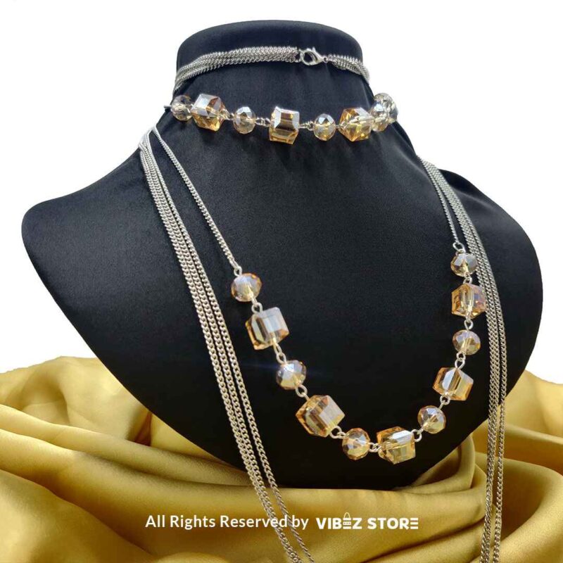 Elegant Crystal Cube and Chain Necklace Set 3 Elegant crystal cube and silver-tone chain necklace set on a black bust with yellow fabric background
