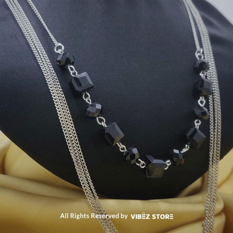 Elegant Crystal Cube and Chain Necklace Set 5 Elegant crystal cube and silver-tone chain necklace set on a black bust with yellow fabric background