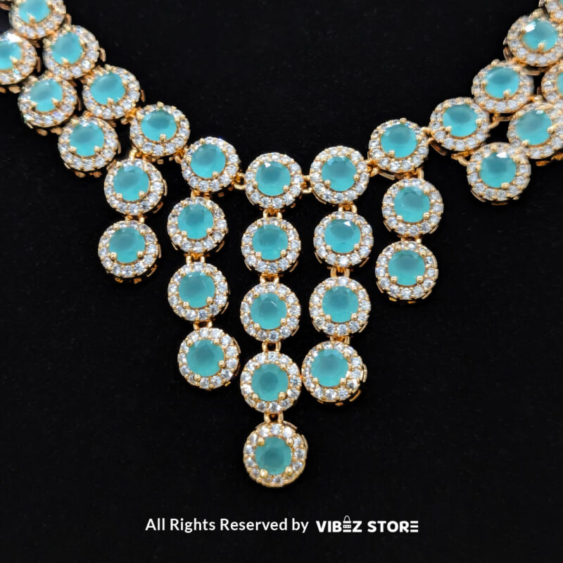 Elegant Aqua Blue Gemstone Jewelry Set 1 Gold-tone jewelry set with aqua blue gemstones, including a necklace, earrings, bracelet, and ring, elegantly displayed by Vibez Store.