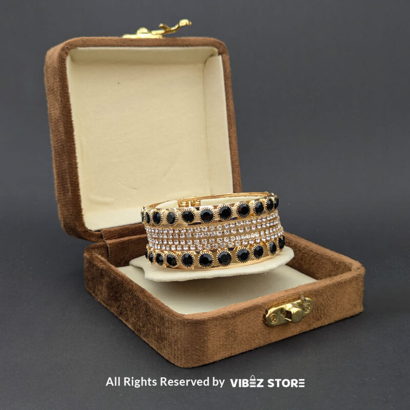 Gold-Plated Black Stone and Crystal Bangle Set 2 Gold-plated bangle set with black stones and crystal embellishments on a black background