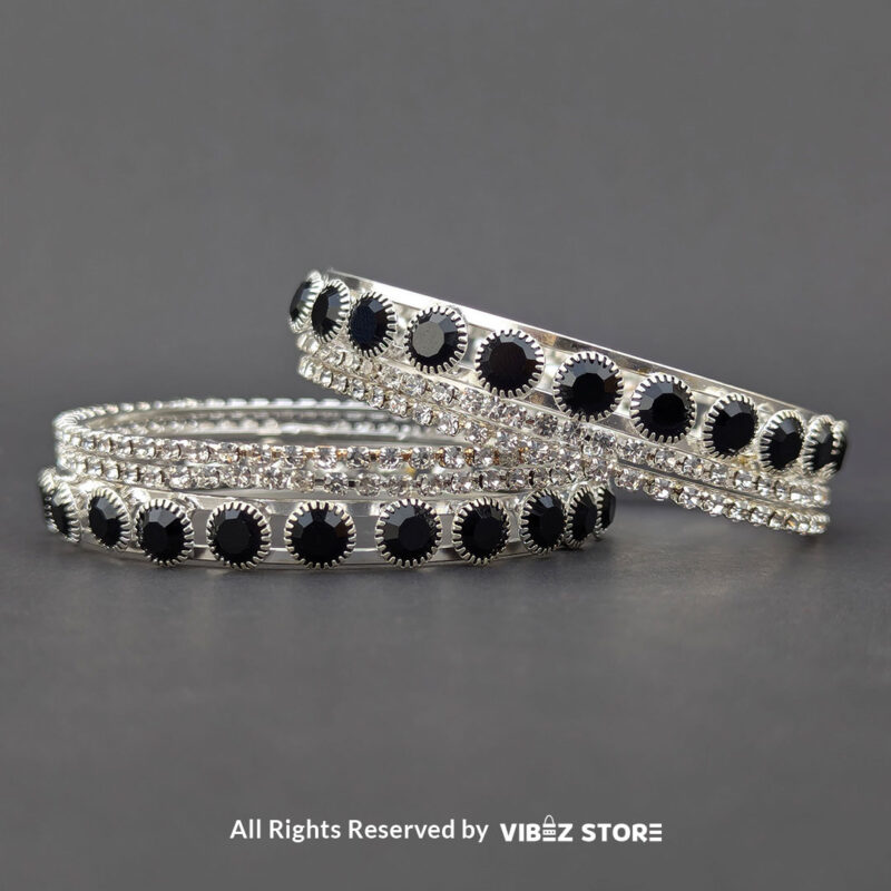Silver Crystal and Black Stone Bangle Set 1 Silver-tone bangle set with black stones and crystal accents on a black fabric background
