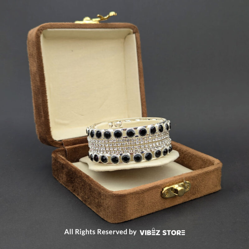 Silver Crystal and Black Stone Bangle Set 2 Silver-tone bangle set with black stones and crystal accents on a black fabric background