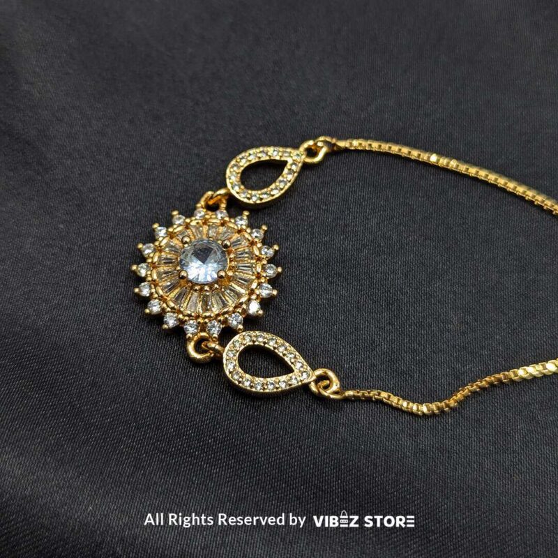 Gold-Tone Adjustable Sunburst Crystal Bracelet 1 Gold-tone adjustable bracelet with sunburst crystal centerpiece and teardrop accents on black fabric background