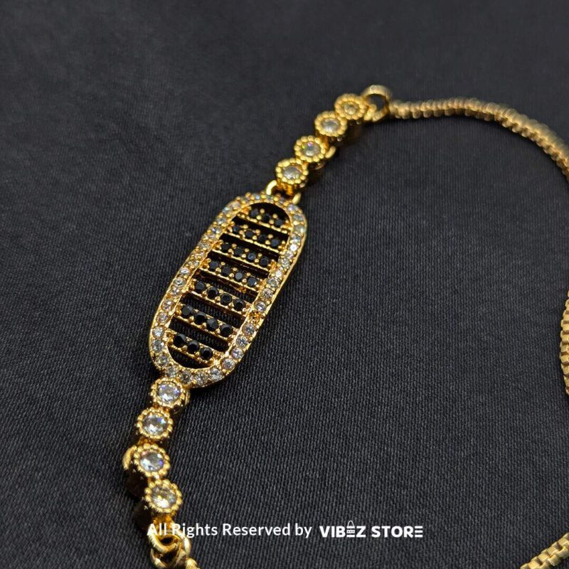 Gold Adjustable Bracelet with Oval Crystal Design 1 Gold adjustable bracelet with oval crystal centerpiece and adjustable chain on black fabric background