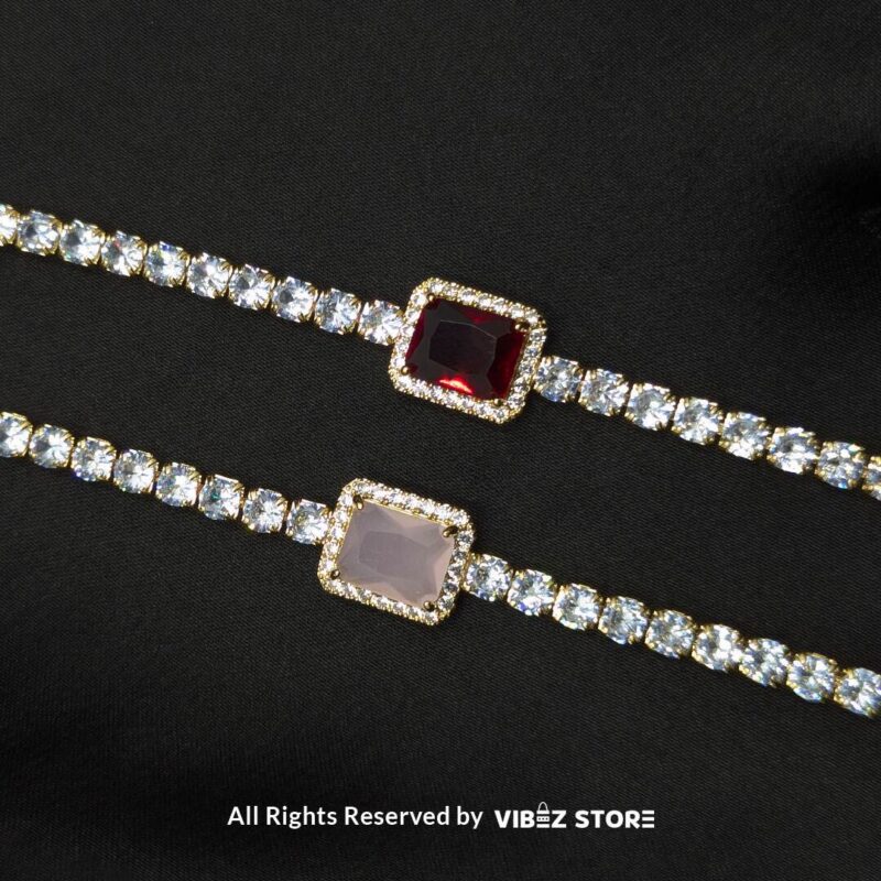 Crystal-Studded Gold Bracelets with Square Gemstone Centerpiece 1 Two crystal-studded gold bracelets with square gemstone centerpieces in ruby red and soft pink on a black fabric background.
