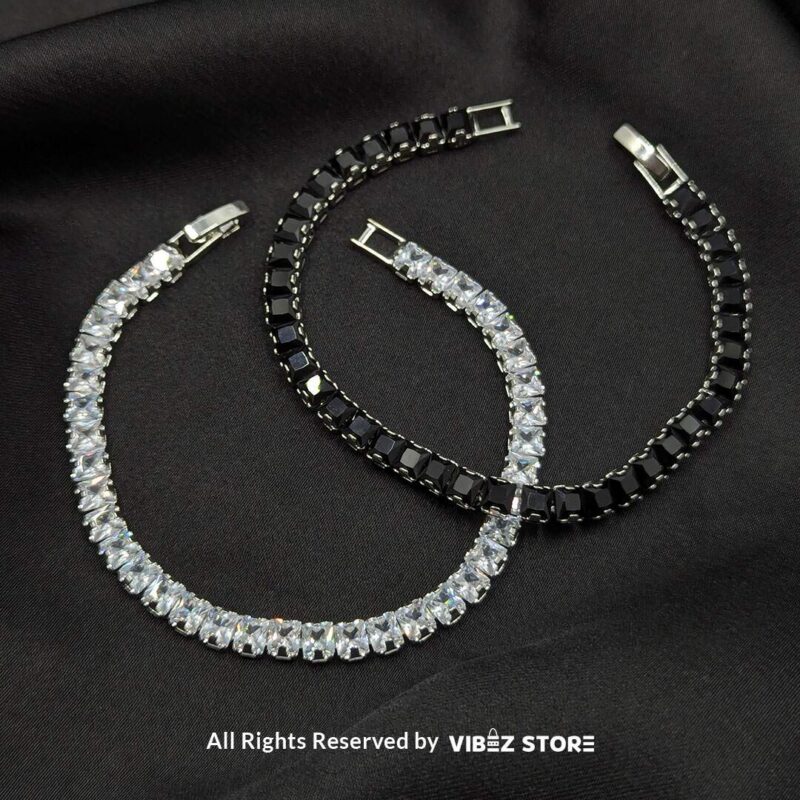 Dual Crystal Tennis Bracelets – Black & White Stones 1 Two crystal tennis bracelets with black and white square-cut stones laid on a black fabric background.