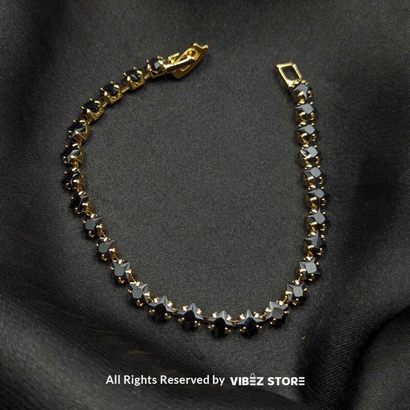 Gold & Silver Starstone Crystal Bracelets – Dual-Tone 5 Two starstone crystal bracelets featuring black stones, one with a gold-tone finish and the other with a silver-tone finish, laid on a black fabric background.