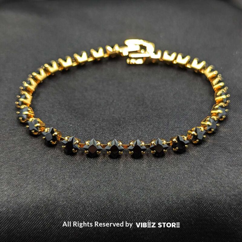 Gold & Silver Starstone Crystal Bracelets – Dual-Tone 4 Two starstone crystal bracelets featuring black stones, one with a gold-tone finish and the other with a silver-tone finish, laid on a black fabric background.