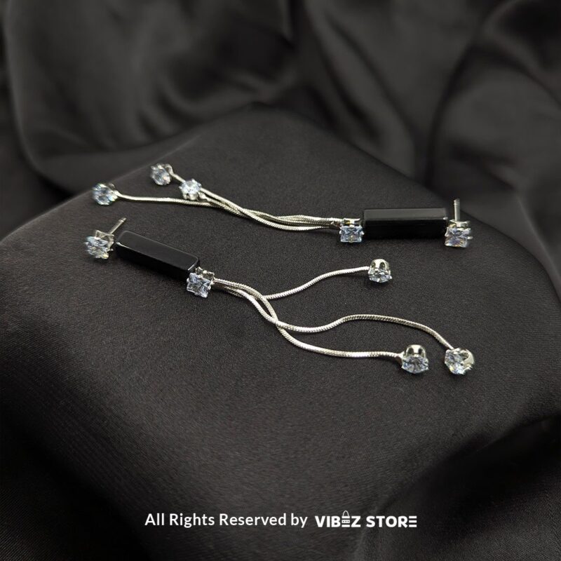 Silver Drape Earrings with Black Accent 1 Stylish silver drape earrings with black accents and sparkling cubic zirconia details displayed on a black satin fabric.