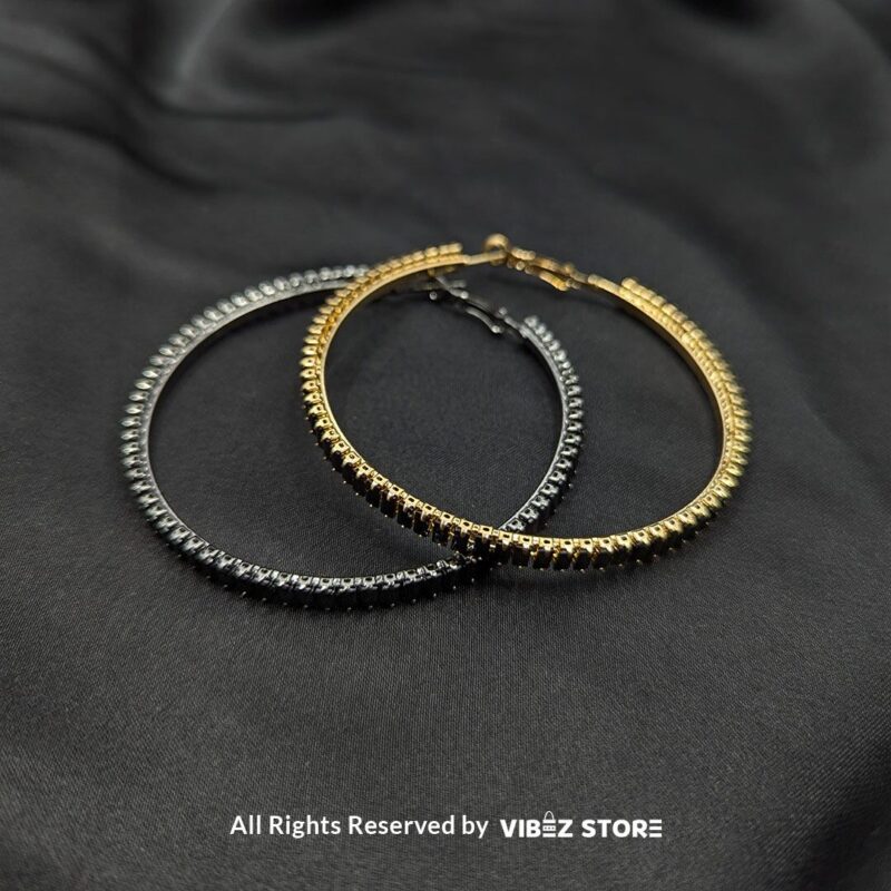 Crystal Hoop Earrings 1 Crystal hoop earrings in gold and black displayed elegantly on a black fabric background.