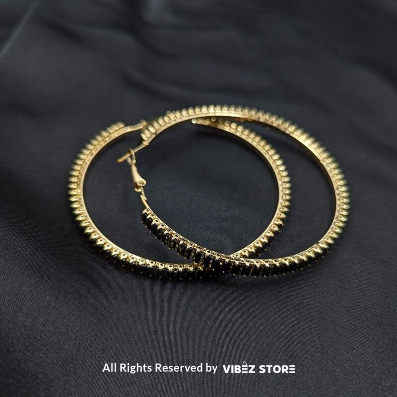 Crystal Hoop Earrings 3 Crystal hoop earrings in gold and black displayed elegantly on a black fabric background.