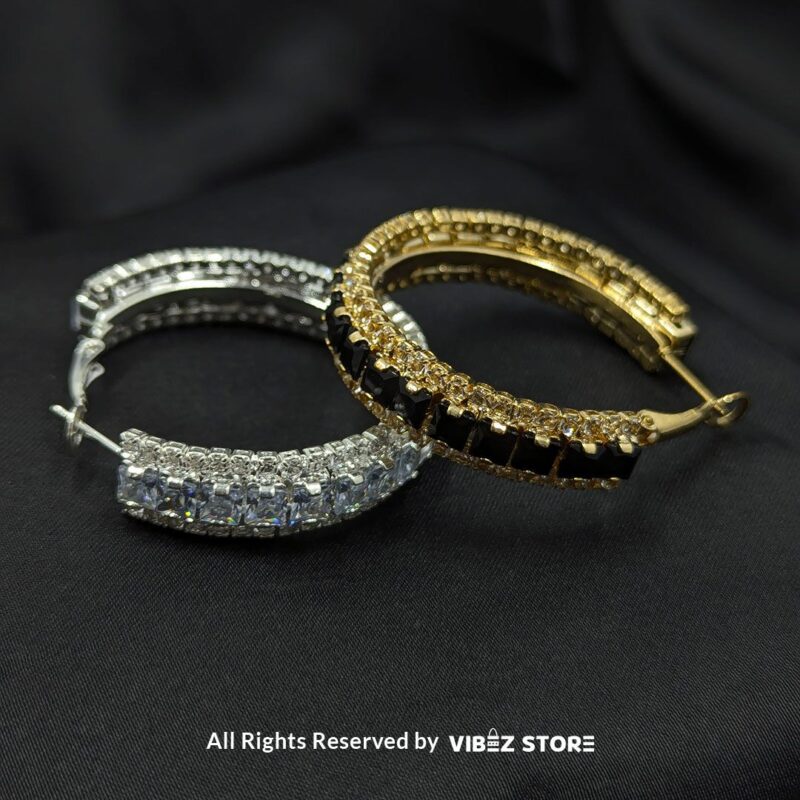 Elegant Crystal Hoop Earrings 1 Gold hoop earrings with black crystals and silver hoop earrings with clear crystals displayed against a black fabric background.