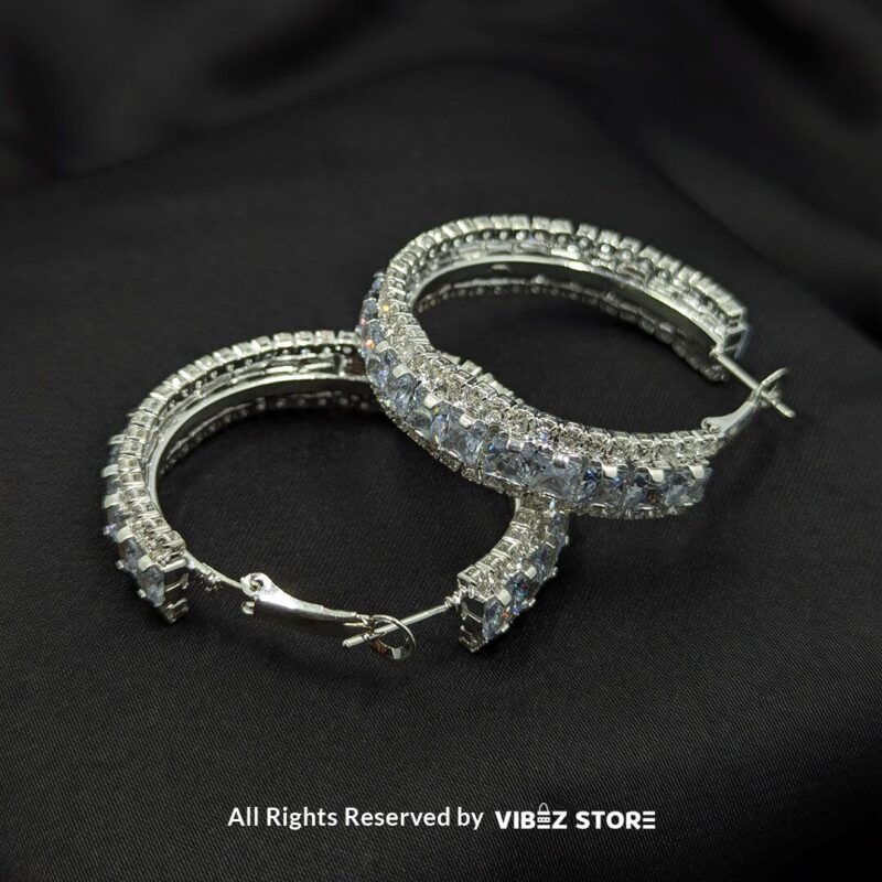 Elegant Crystal Hoop Earrings 3 Gold hoop earrings with black crystals and silver hoop earrings with clear crystals displayed against a black fabric background.