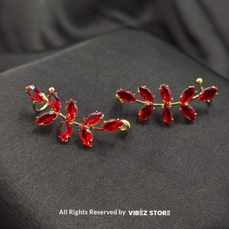 Leaf Design Red Crystal Earrings 1 Golden earrings with vibrant marquise-cut red crystals arranged in a leaf pattern displayed on a black fabric background.