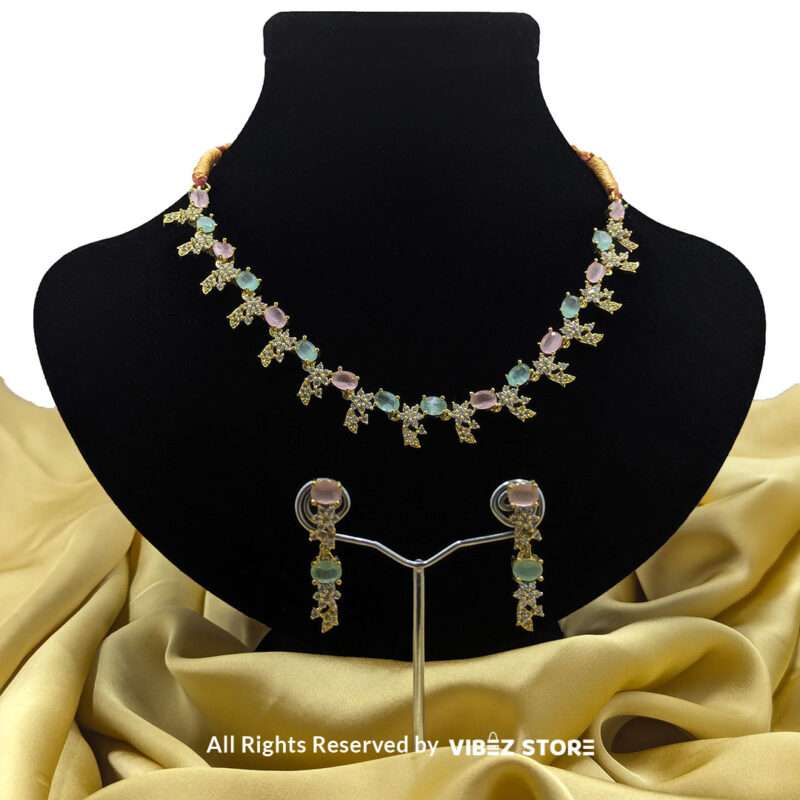Gold-Plated Pastel Gemstone Necklace Set with Earrings 1 Gold-plated pastel gemstone necklace with matching drop earrings on a black display, featuring pink and green stones in floral motifs, ideal for weddings and festive occasions.