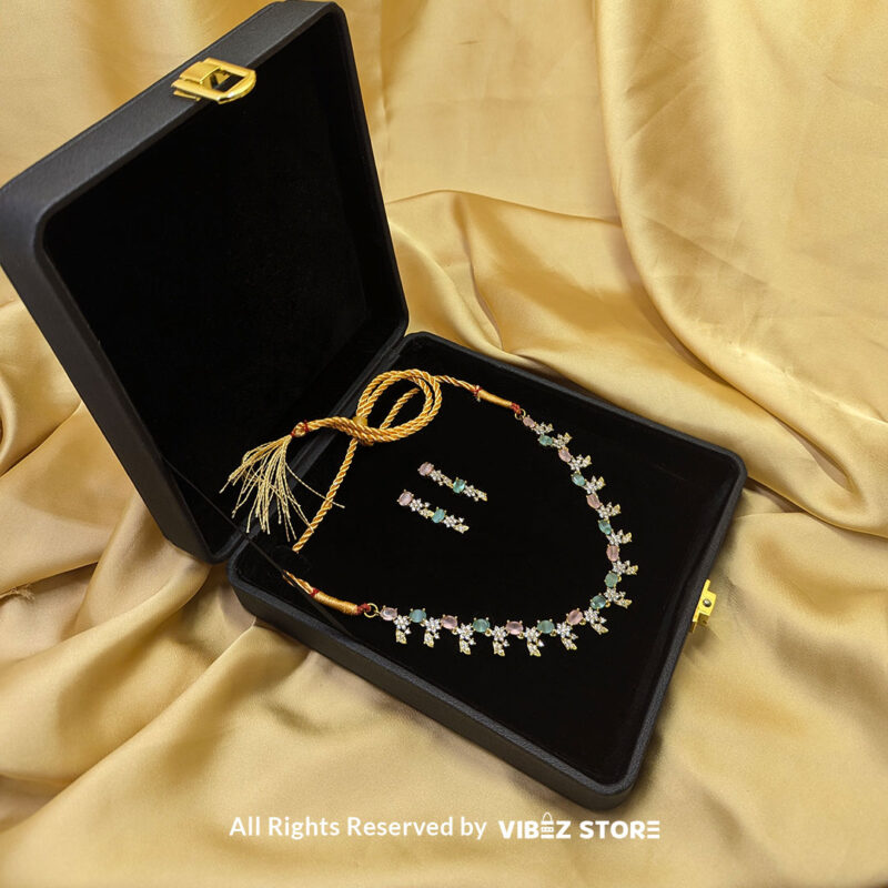 Gold-Plated Pastel Gemstone Necklace Set with Earrings 3 Gold-plated pastel gemstone necklace with matching drop earrings on a black display, featuring pink and green stones in floral motifs, ideal for weddings and festive occasions.