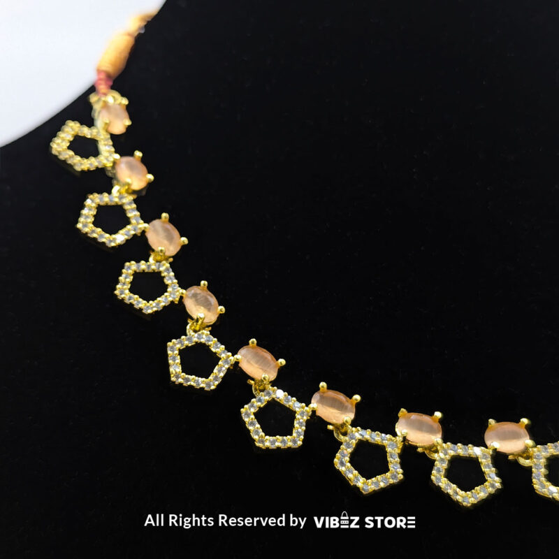 Gold-Plated Peach Gemstone Necklace Set with Earrings 3 Gold-plated necklace set featuring peach gemstones and a hexagonal design, paired with matching drop earrings on a black display, perfect for weddings and parties.