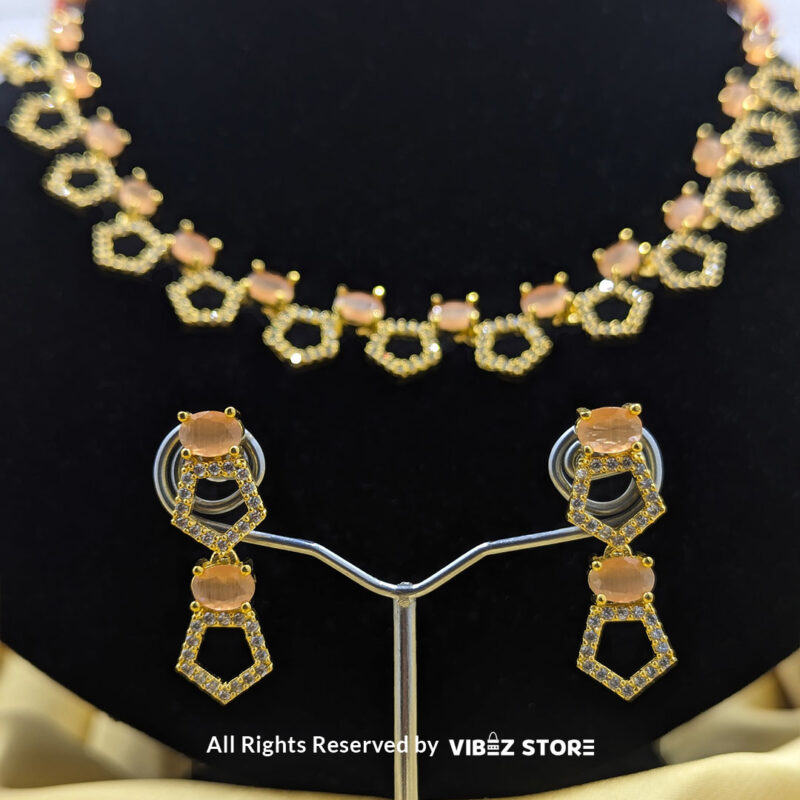 Gold-Plated Peach Gemstone Necklace Set with Earrings 4 Gold-plated necklace set featuring peach gemstones and a hexagonal design, paired with matching drop earrings on a black display, perfect for weddings and parties.