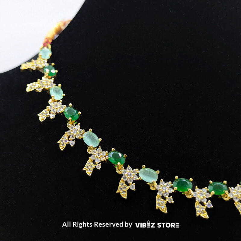 Gold-Plated Green Gemstone Necklace Set with Earrings 4 Gold-plated necklace set with vibrant green gemstones and a matching earring pair displayed on a black mannequin, perfect for weddings and formal events.