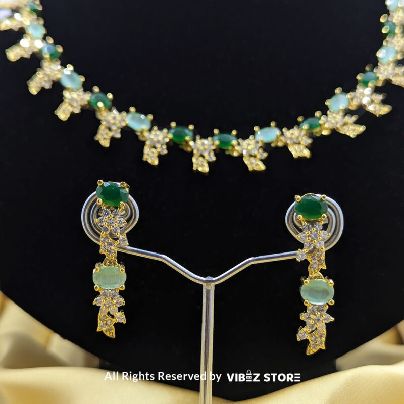 Gold-Plated Green Gemstone Necklace Set with Earrings 5 Gold-plated necklace set with vibrant green gemstones and a matching earring pair displayed on a black mannequin, perfect for weddings and formal events.