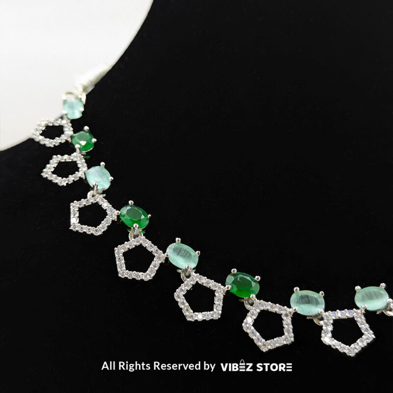 Silver-Plated Green Gemstone Necklace Set with Earrings 4 Silver-plated necklace with green gemstones in a geometric design, paired with matching drop earrings, displayed on a black mannequin.