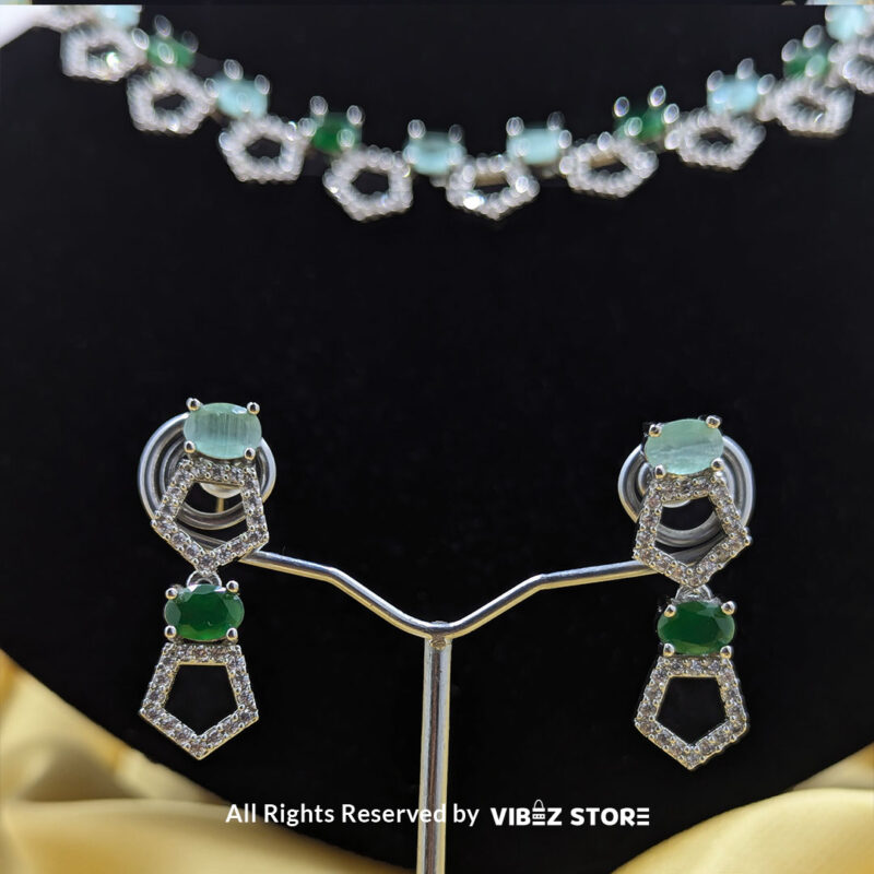 Silver-Plated Green Gemstone Necklace Set with Earrings 5 Silver-plated necklace with green gemstones in a geometric design, paired with matching drop earrings, displayed on a black mannequin.