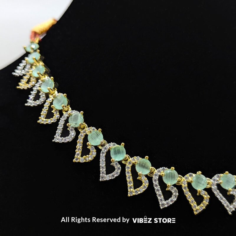 Dual-Tone Green Gemstone Necklace Set with Earrings 4 Dual-tone green gemstone necklace set with matching drop earrings, displayed on a black mannequin with a golden fabric backdrop.