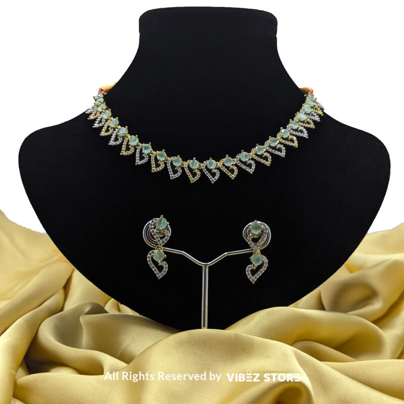 Dual-Tone Green Gemstone Necklace Set with Earrings 1 Dual-tone green gemstone necklace set with matching drop earrings, displayed on a black mannequin with a golden fabric backdrop.