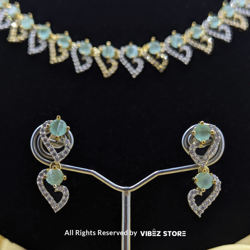 Dual-Tone Green Gemstone Necklace Set with Earrings 5 Dual-tone green gemstone necklace set with matching drop earrings, displayed on a black mannequin with a golden fabric backdrop.