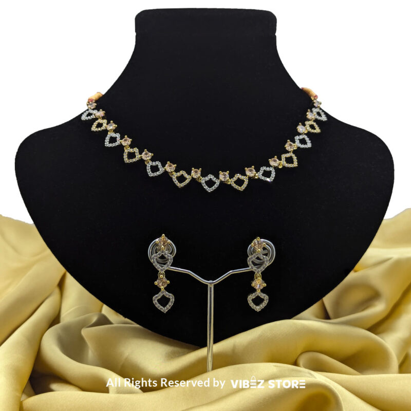 Heart Design Necklace Set with Earrings 1 Heart-shaped necklace set with sparkling stones and matching earrings, displayed on a black mannequin with a golden fabric backdrop.