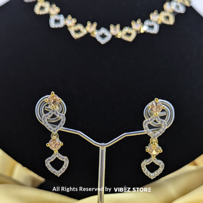 Heart Design Necklace Set with Earrings 5 Heart-shaped necklace set with sparkling stones and matching earrings, displayed on a black mannequin with a golden fabric backdrop.