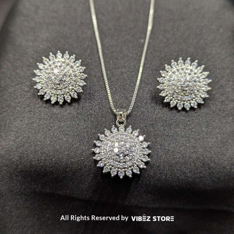Radiant Starburst Pendant and Earrings Set 1 Starburst-shaped pendant and matching earrings adorned with shimmering crystals, displayed on a sleek black fabric.
