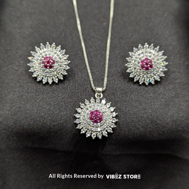 Ruby Starburst Pendant and Earrings Set 1 Ruby starburst pendant with matching earrings, featuring shimmering crystals and a vibrant ruby centerpiece, displayed on a sleek black fabric.