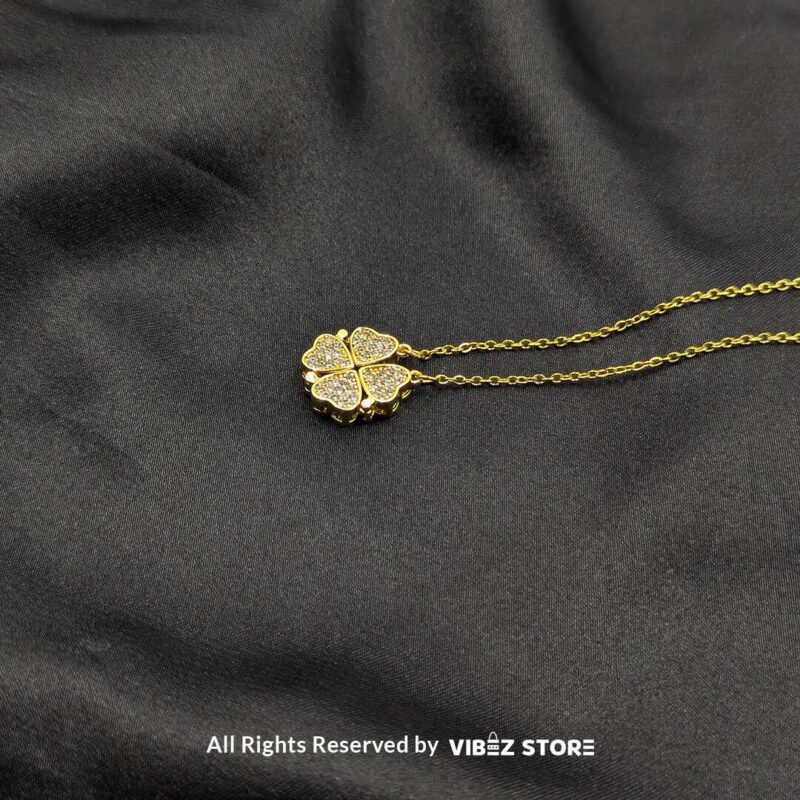 Magnetic Gold Heart Locket with Pave Crystal Design 3 Magnetic gold-tone locket with interconnected heart shapes adorned with pave crystals, displayed on a black fabric background.