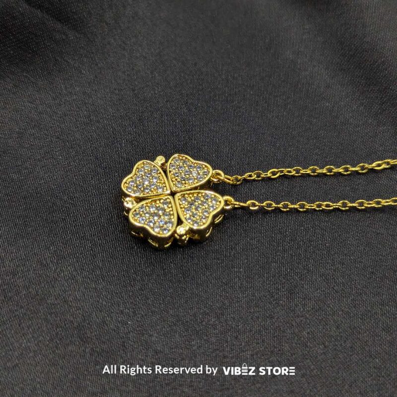 Magnetic Gold Heart Locket with Pave Crystal Design 1 Magnetic gold-tone locket with interconnected heart shapes adorned with pave crystals, displayed on a black fabric background.