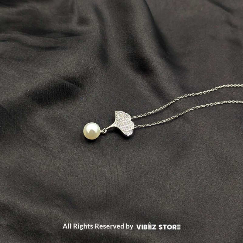 Elegant Pearl Drop Leaf Locket 1 A silver locket featuring a sparkling leaf design with a pearl drop, perfect for adding elegance to any outfit.