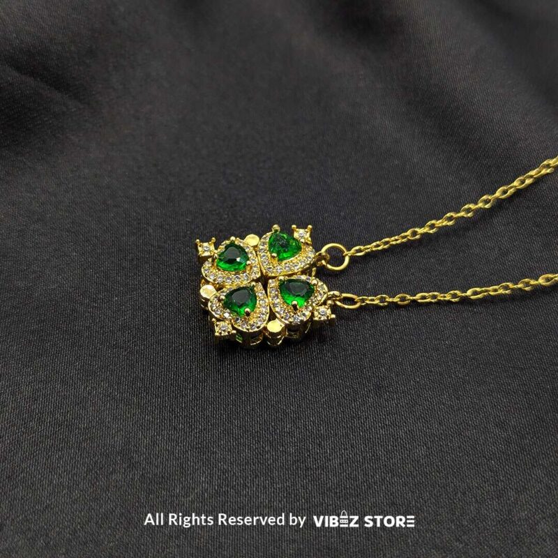 Magnetic Heart-Shaped Gold Locket with Green Gemstones 1 Gold magnetic heart-shaped locket featuring green gemstones and pave crystals, displayed on a black fabric background.