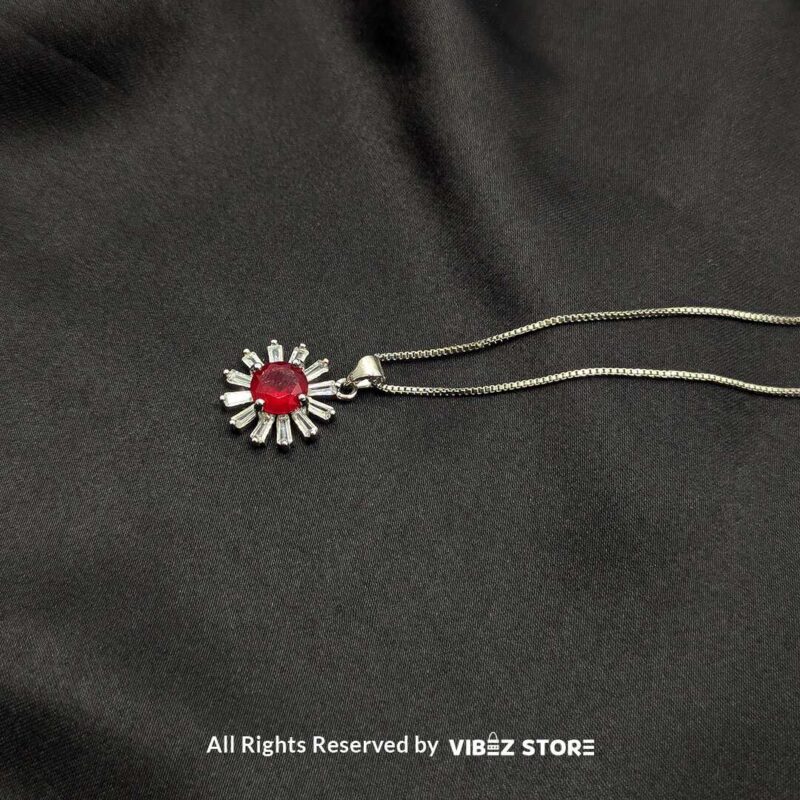 Radiant Sunburst Gemstone Locket Collection 5 A collection of silver sunburst lockets featuring vibrant gemstones in white, green, red, and black, laid on a black fabric background.