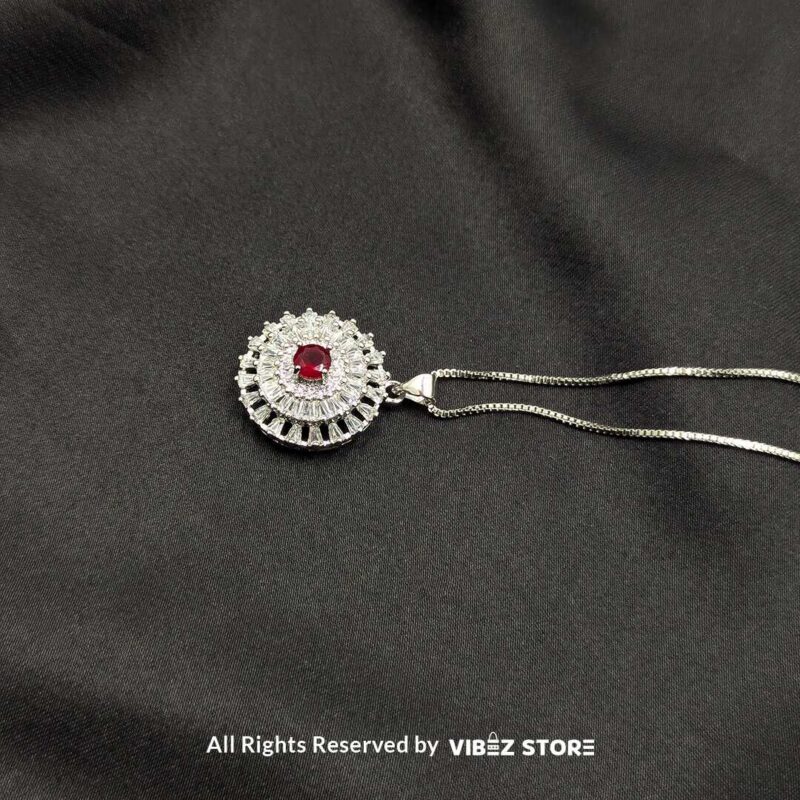 Gemstone Round Locket with Crystal Halo 4 A silver-tone round locket with a vibrant gemstone (choose ruby red, sapphire blue, or clear crystal) surrounded by intricate crystal detailing, displayed on a black fabric background.