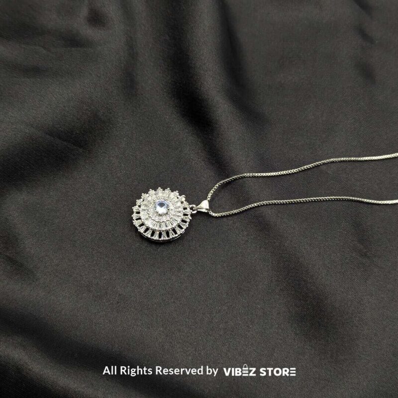 Gemstone Round Locket with Crystal Halo 2 A silver-tone round locket with a vibrant gemstone (choose ruby red, sapphire blue, or clear crystal) surrounded by intricate crystal detailing, displayed on a black fabric background.