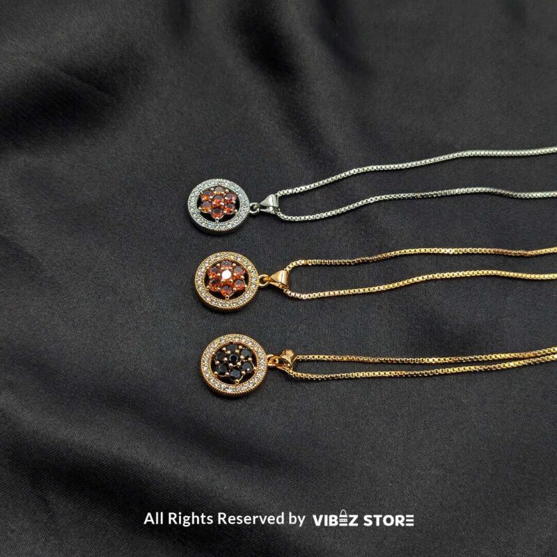 Floral Gemstone Round Locket with Crystal Halo 1 Three round lockets featuring floral gemstone designs (black, amber, and red) surrounded by crystal halos, displayed with gold-tone and silver-tone chains on a black fabric background.
